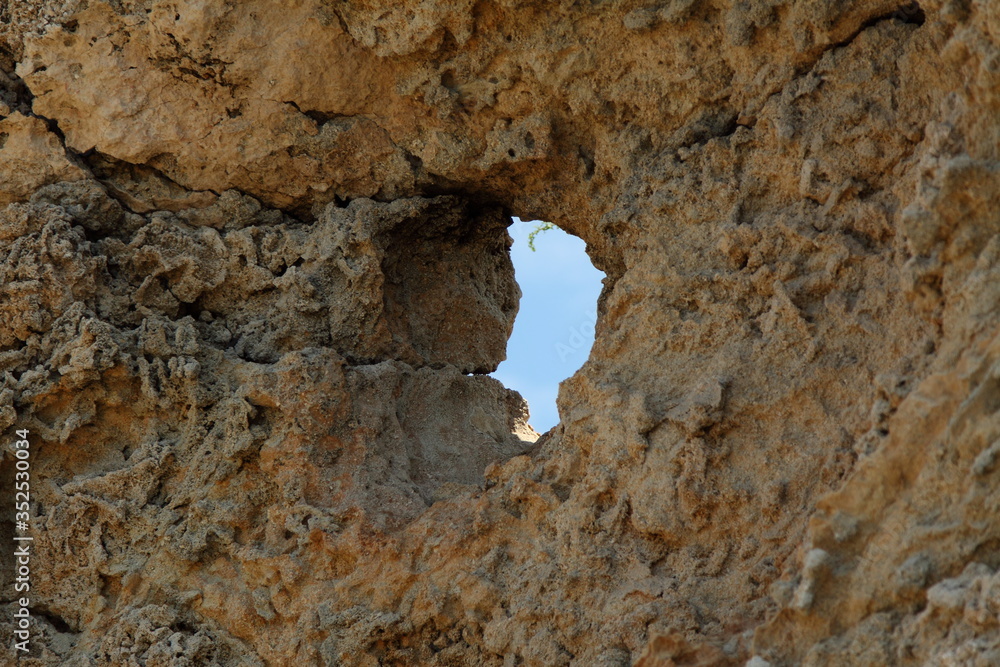 Rock hole created by nature. Closeup rock erosion holes sea wall. Wallpaper and background. External texture.
