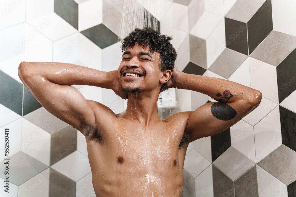 Photo of half-naked african american man smiling while taking shower Photo of half-naked african american man smiling while taking shower