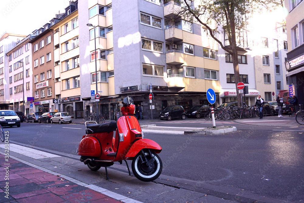 Urban view. Red retro motorbike on the street. Urban PC wallpaper, Stylish texture background. Cologne streets. Red scooter. Motorcycle background.