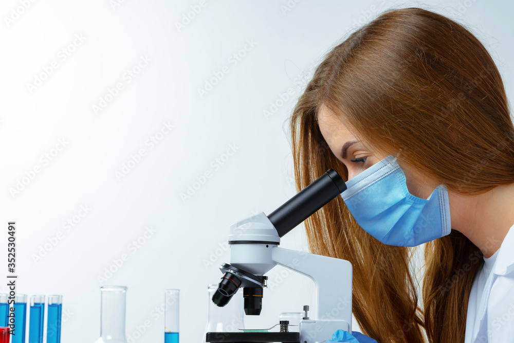 Woman scientist looking through a microscope in laboratory