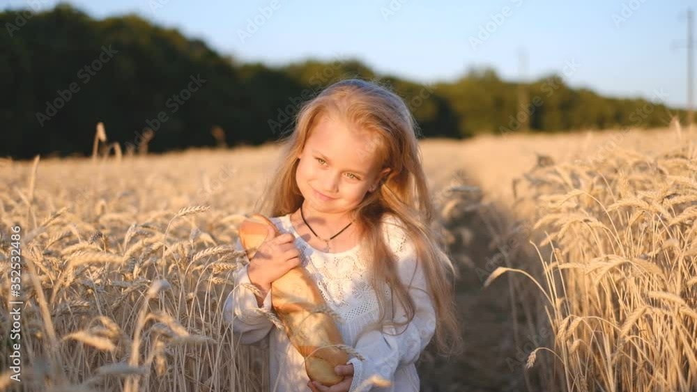 Joyful girl holding a fresh baguette in a wheat field, happiness Joyful girl holding a fresh baguette in a wheat field, happiness