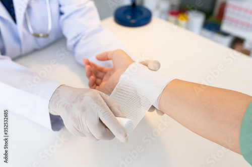 Close-up hand wear medical gloves Of Doctor Hand Tying Bandage On The hand Of Patient In Clinic, osteophytes and heel, fascia