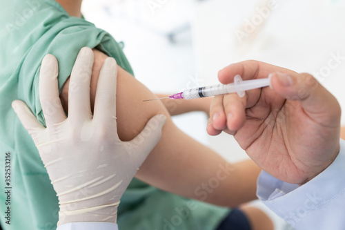 Close up of a Doctor making a vaccination in the shoulder of patient  Flu Vaccination Injection on Arm  coronavirus  covid-19 vaccine disease preparing for human clinical trials vaccination shot..