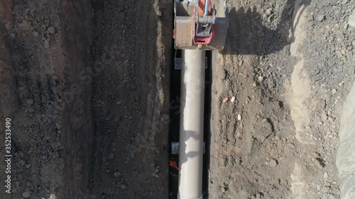Concrete pipe tube installation. Aerial above men at work outside with heavy machinery to connect and install water or sewerage pipeline in a digging soil land