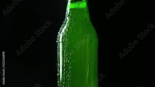 green bottle with light beer and condensate water drops isolated on black