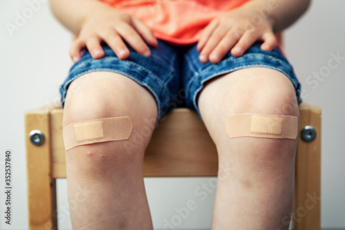 child knees with adhesive bandage strips