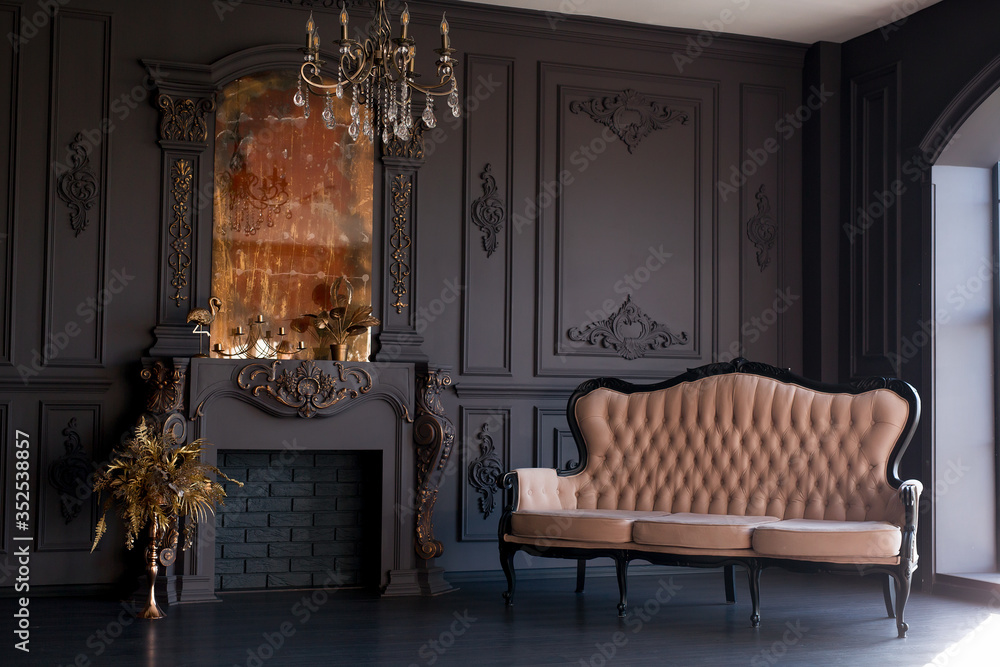 Fototapeta premium Black room interior with a vintage sofa, chandelier, mirror and fireplace