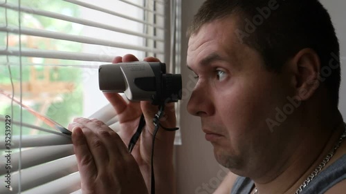 A strange man looks through binoculars photo