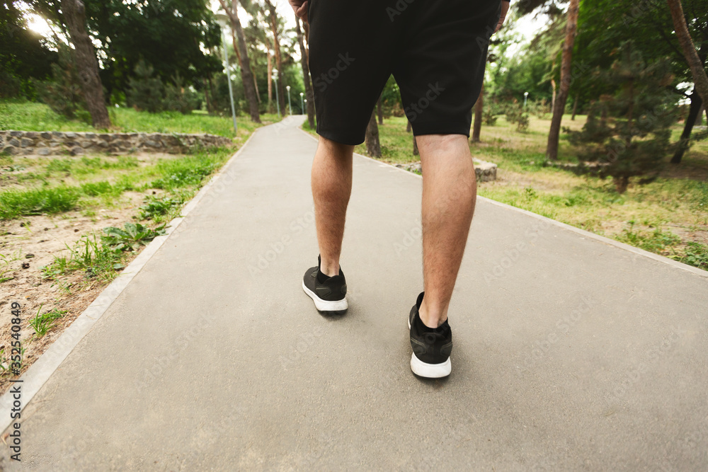 Sportsman running walking in the park, back view of legs Sportsman running walking in the park, back view of legs