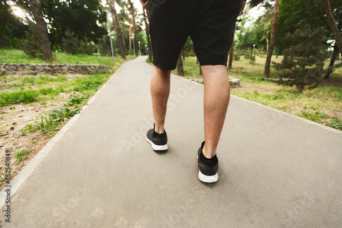 Sportsman running walking in the park, back view of legs