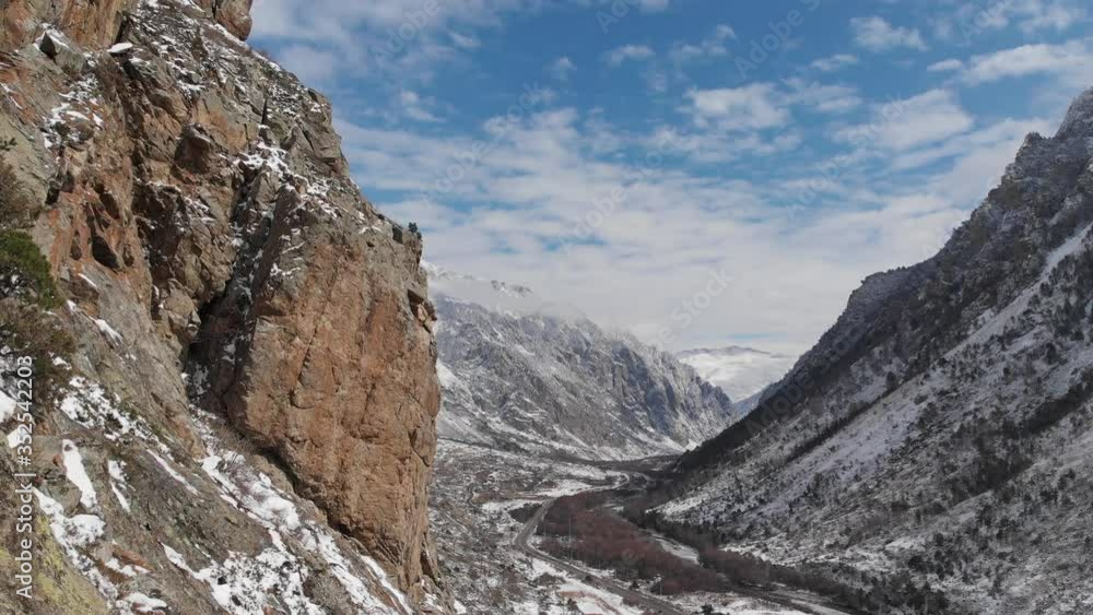 An aerial view of the span next to the rock on the mountain gorge in early spring powdered with snow. An aerial view of the span next to the rock on the mountain gorge in early spring powdered with snow.