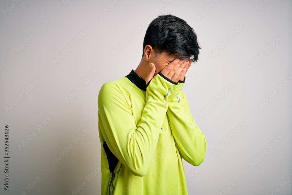 Young handsome sportsman doing sport wearing sportswear over isolated white background with sad expression covering face with hands while crying. Depression concept. Young handsome sportsman doing sport wearing sportswear over isolated white background with sad expression covering face with hands while crying. Depression concept.