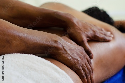 Dark-skinned hands give a relaxing massage to man. dark skin lying on the stretcher