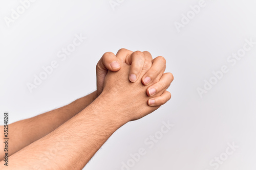 Hand of caucasian young man showing fingers over isolated white background praying with hands clasped, fold fingers religious gesture © Krakenimages.com