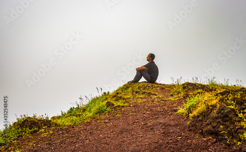 hiker resting at hilltop with breathtaking mountain layers in background