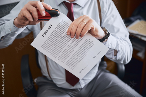 Male hands holding stapler and paper document