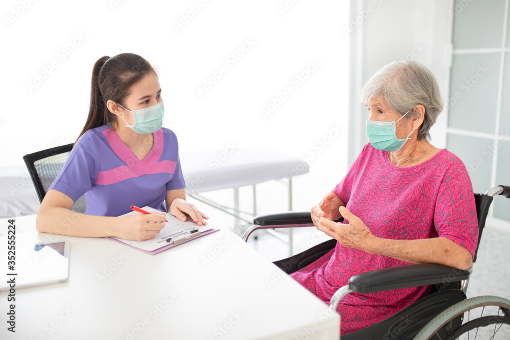 asian healthcare worker screening old patient in hospital, she assess and write report on medical record chart, elderly health check up, they wear surgical mask, corona virus protection asian healthcare worker screening old patient in hospital, she assess and write report on medical record chart, elderly health check up, they wear surgical mask, corona virus protection