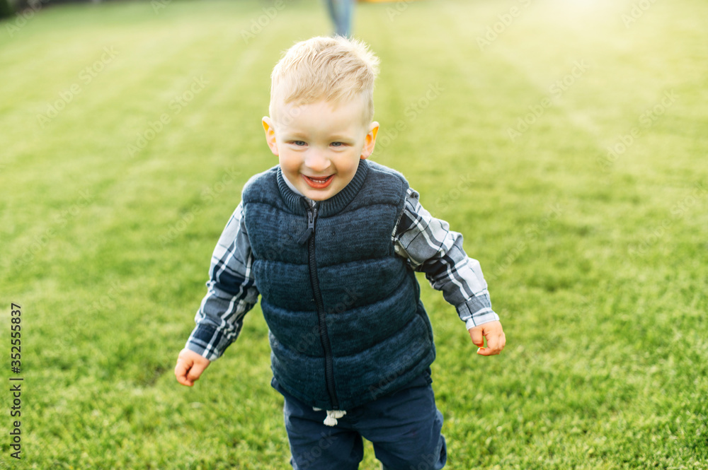 Laughing toddler boy is running on the green lawn outdoors. Happy childhood Laughing toddler boy is running on the green lawn outdoors. Happy childhood