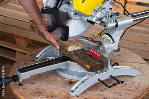 miter saw for cutting a tree on a wooden table. A man lays down wooden boards. Tool for carpentry.