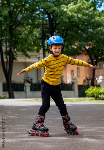 A nice and smiling boy learns to ride roller skates