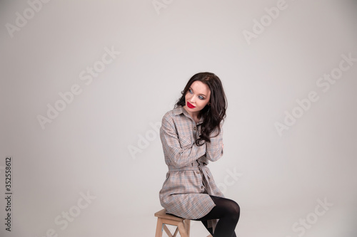 Beautiful sexy girl in a shirt sits on a chair in a photo studio. Copy space