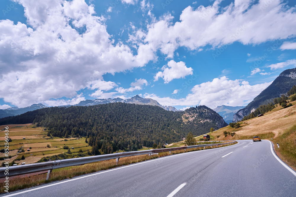Naklejka premium Asphalt road in Alps mountains. Road trip concept.
