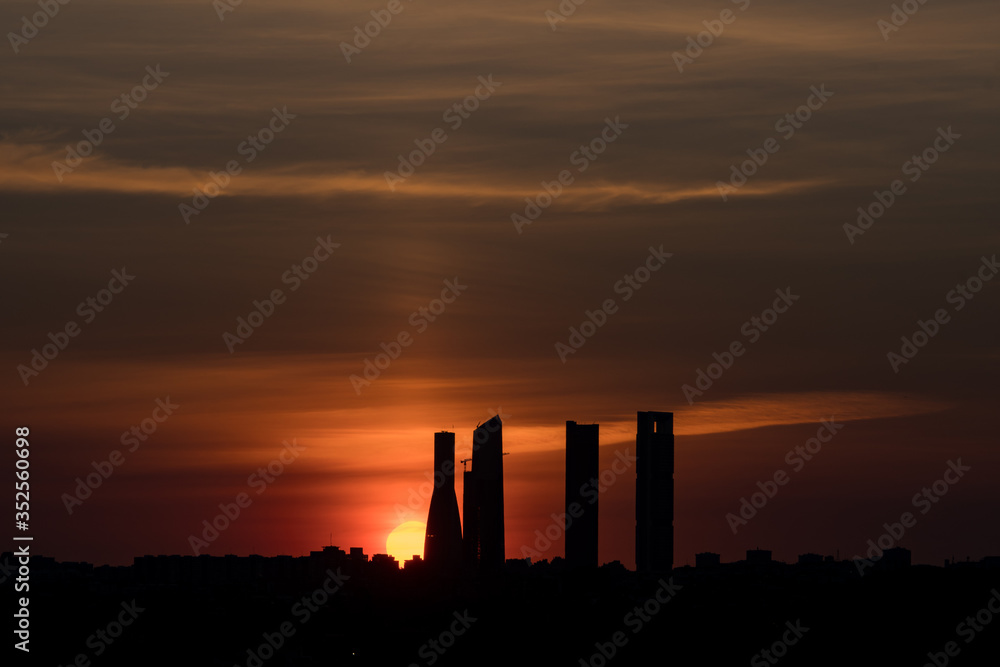 Red sun coming out behind the four towers on silhouette. Beautiful dark sunrise Madrid.
