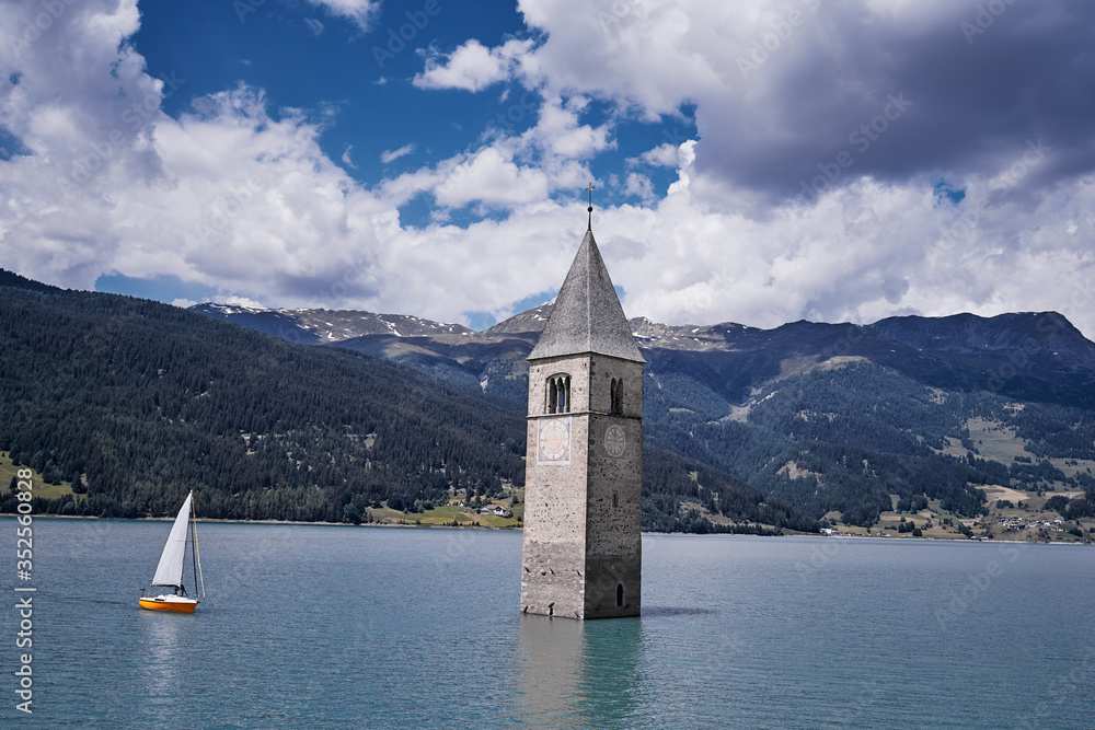 Picturesque summer view of Tower of sunken church in Resia lake. Wonderful  scene of Italian Alps, South Tyrol, Italy, Europe. Traveling concept background.