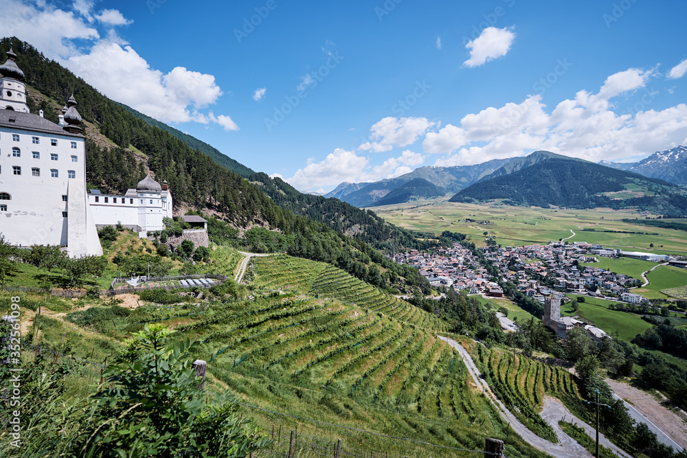 Beautiful summer landscape with ancient monastery in mountains. Benedictine Abbey of Monte Maria in the Venosta valley, South Tyrol, northern Italy, Europe.