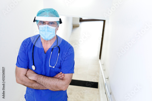 Chirurgo con protezioni e camice blu nella corsia di un ospedale