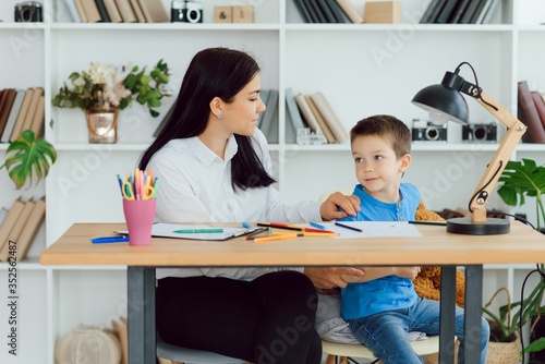 Young female psychologist working with little boy in office