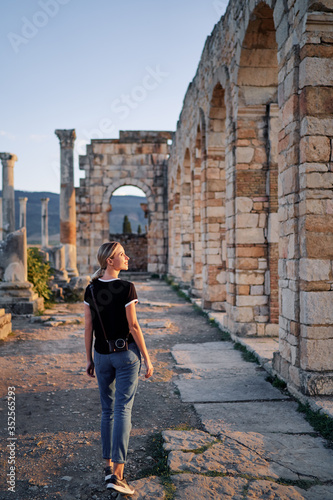 Happy young woman walking on ancient antique city Volubilis. Traveling by Morocco.