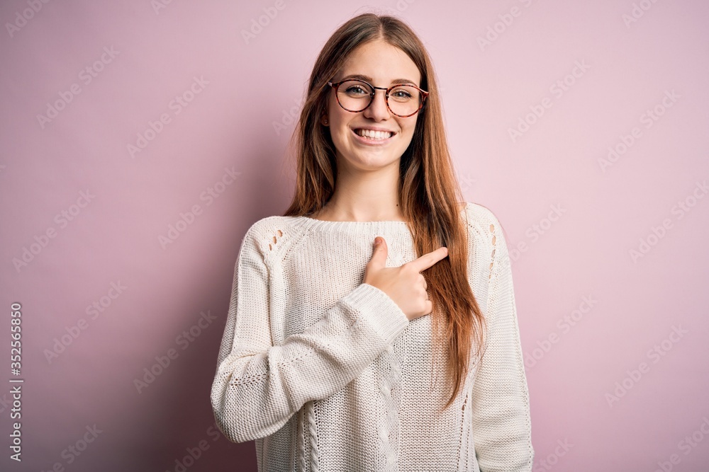 Young beautiful redhead woman wearing casual sweater and glasses over pink background cheerful with a smile on face pointing with hand and finger up to the side with happy and natural expression Young beautiful redhead woman wearing casual sweater and glasses over pink background cheerful with a smile on face pointing with hand and finger up to the side with happy and natural expression