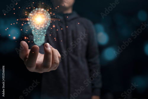 Businessman holding glowing virtual lightbulb with orange light . Creative new business idea concept.