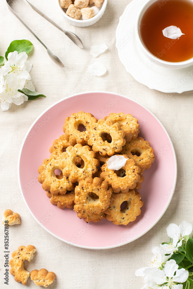 Shortbread in a pink ceramic plate on a light table. A plate of cookies on the table among the flowering trees. A plate full of cookies. Rustic homemade cakes. The view from the top Shortbread in a pink ceramic plate on a light table. A plate of cookies on the table among the flowering trees. A plate full of cookies. Rustic homemade cakes. The view from the top