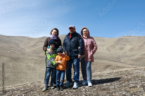 Family posing on rocky ridge of Caucasus background
