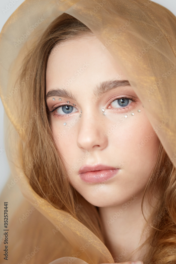 Obraz premium A young girl with a beautiful clean face close-up, with her head covered.