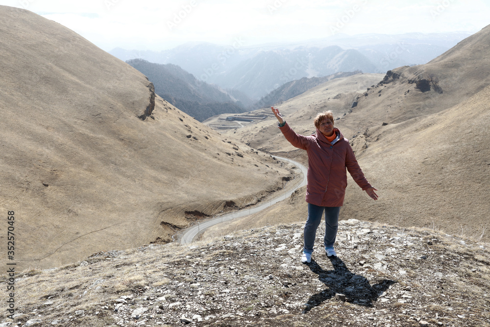 Senior woman posing on rocky ridge of Caucasus background
