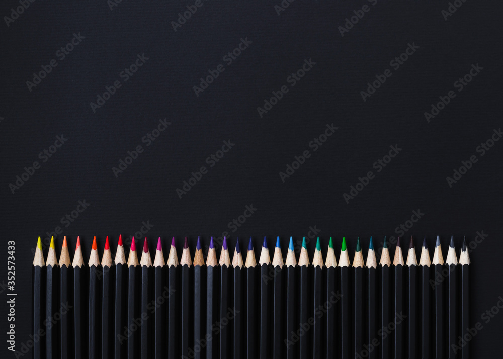 Colored pencil set arranged in line on black background. Stationery backdrop for your design Colored pencil set arranged in line on black background. Stationery backdrop for your design
