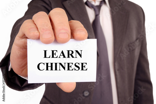 Man holding a card on which is written learn Chinese