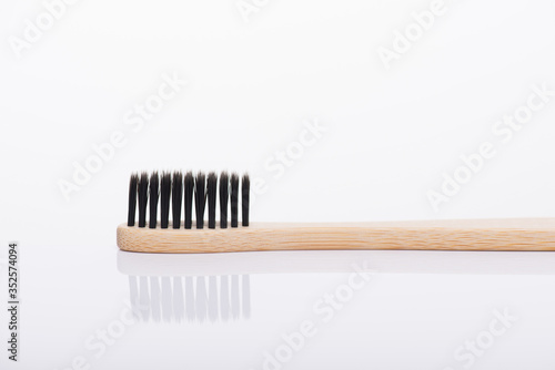 Close-up macro side profile view photo of eco-friendly toothbrush with black color bristle isolated on white background