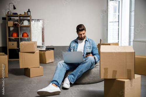 Carefree stylish male with laptop selling his apartmet photo