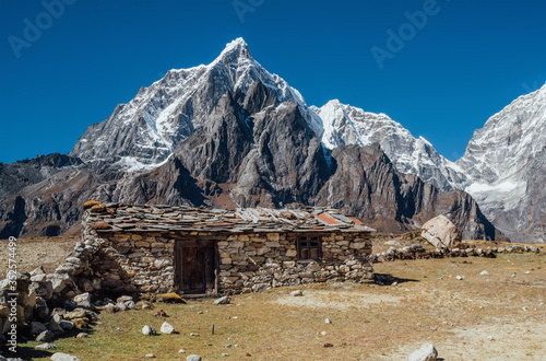 Picturesque view authentic tibetan habitation and stone fence in the Khumbu region in Nepal with majestic Taboche mountain 6501m on background. Remote traveling gems concept image.