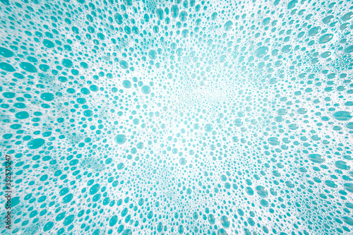 Abstract background made of white foam bubles on aqua color water