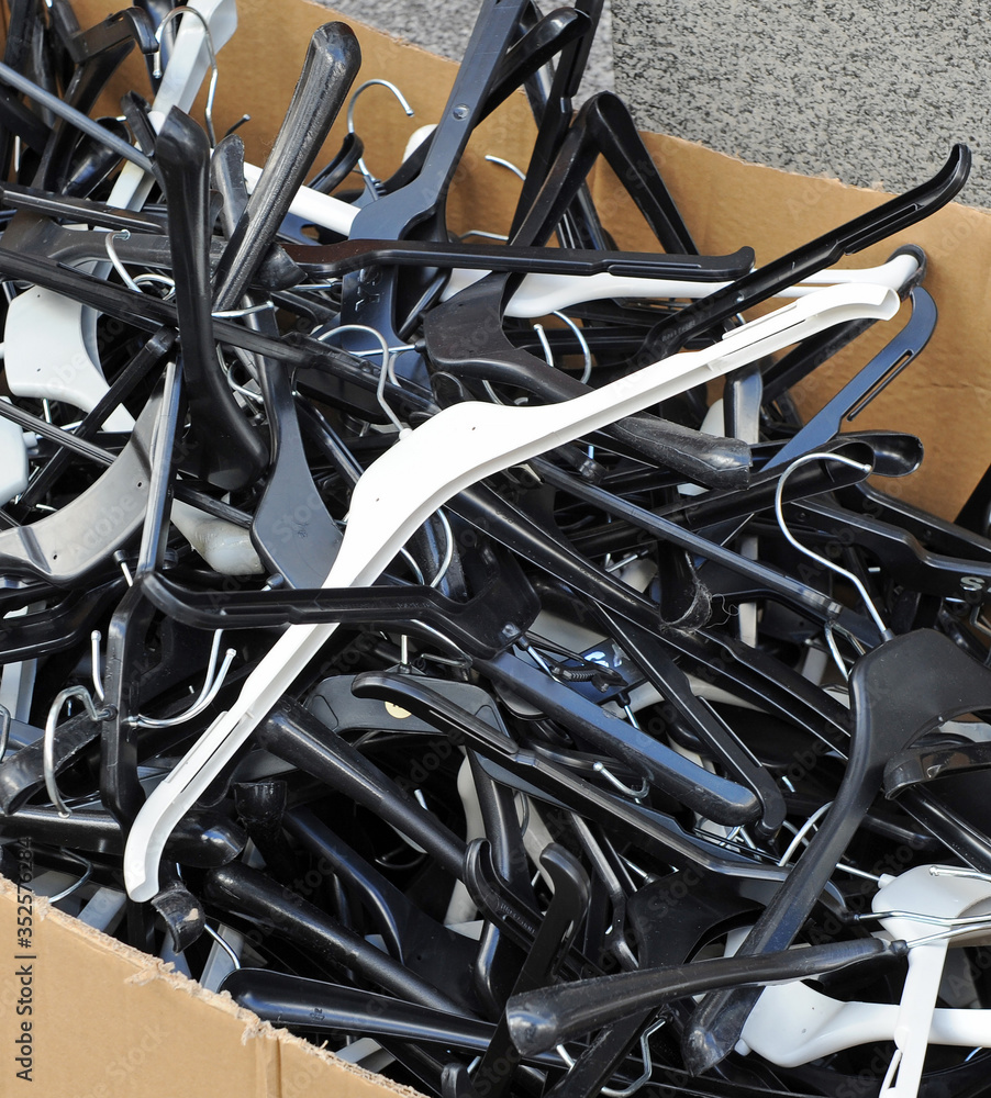 Many plastic hangers from a clothing store to throw it away. Waste of valuable materials on a cardboard box Many plastic hangers from a clothing store to throw it away. Waste of valuable materials on a cardboard box