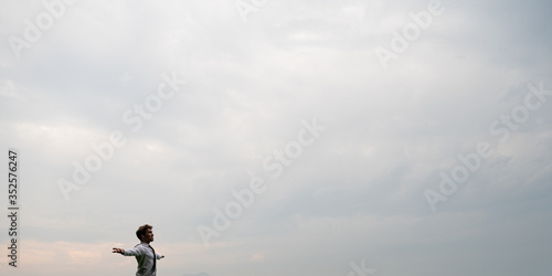 Young businessman meditating and relaxing as he stands outside under a cloudy sky