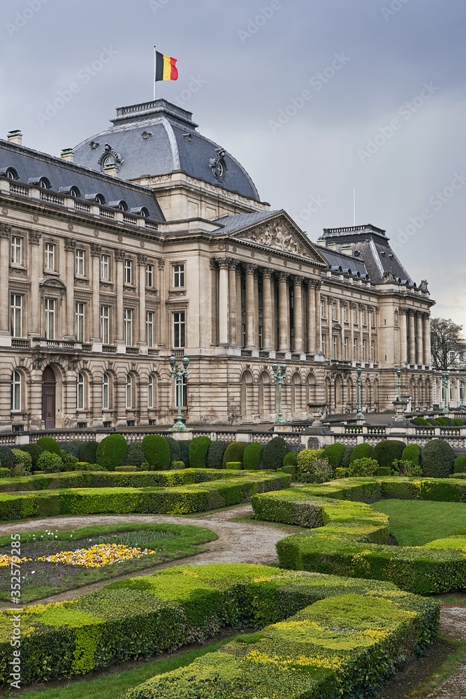 The Royal Palace in Brussels, Belgium from the northeastern corner in spring. National flag of the Kingdom of Belgium waving on top.