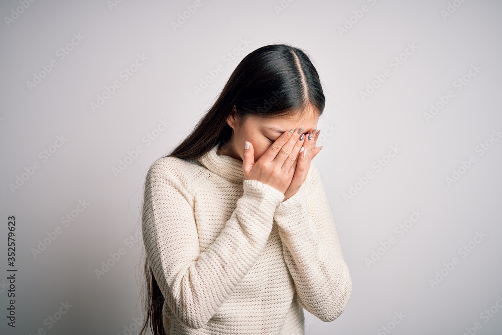 Young beautiful asian woman wearing casual sweater standing over isolated background with sad expression covering face with hands while crying. Depression concept. Young beautiful asian woman wearing casual sweater standing over isolated background with sad expression covering face with hands while crying. Depression concept.