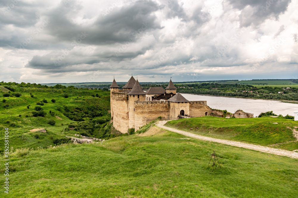 Khotyn Fortress castle in Ukraine, river on a background of dark clouds on a cloudy windy day in summer. Horizontal orientation.