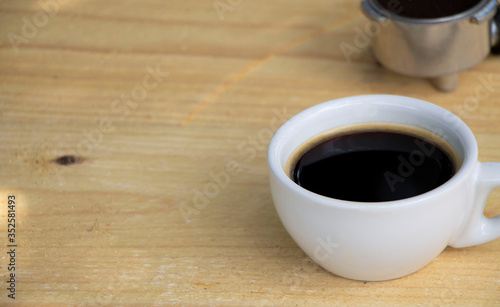 Black coffee in a white cup on natural color wooden table. Relaxing time, lifestyle concept.
